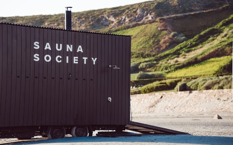 Mobile sauna on beach with greenery background