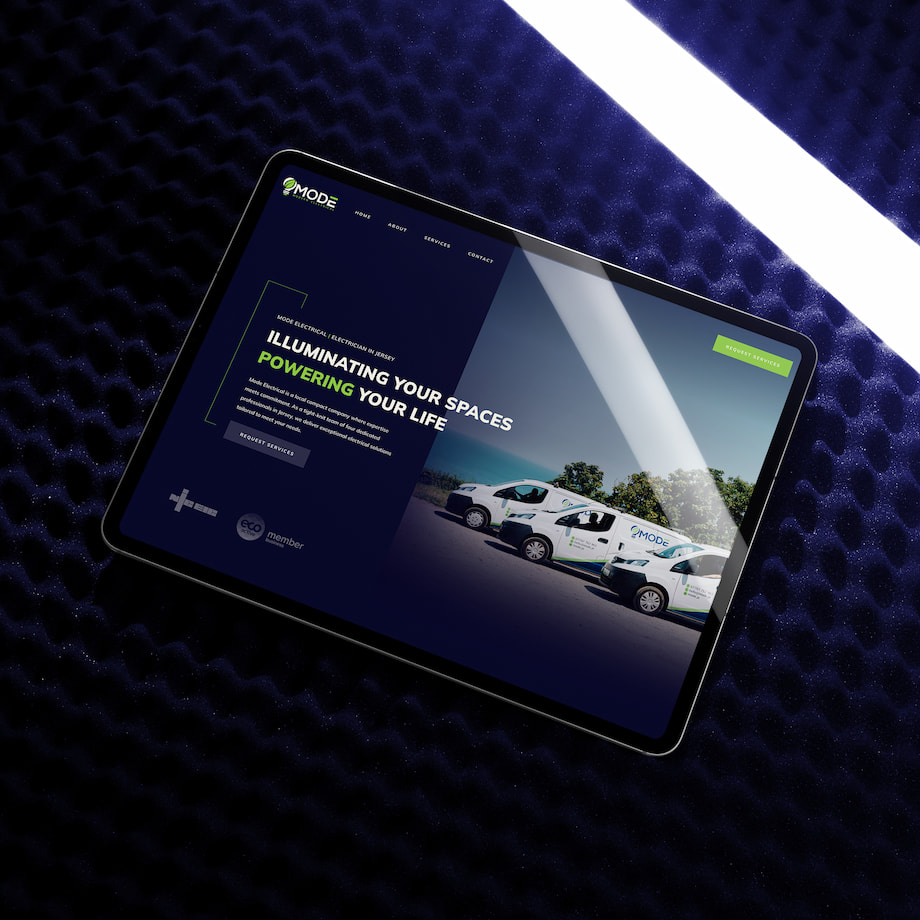 Tablet displaying Mode Electrical website on dark surface.